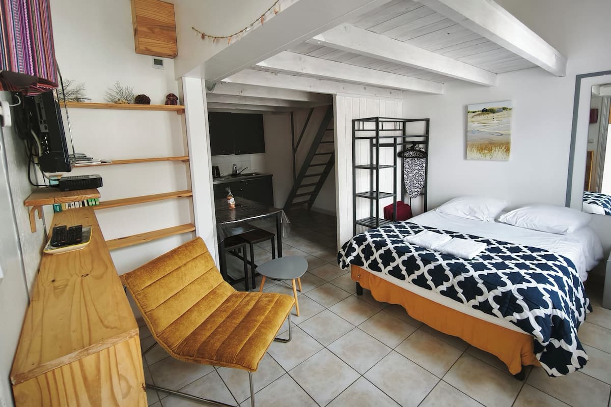 Une chambre à coucher comprenant un lit, une chaise, un bureau et un escalier menant à un niveau supérieur.
