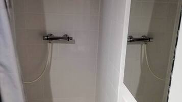 Een badkamer met een douche, wastafel en spiegel.