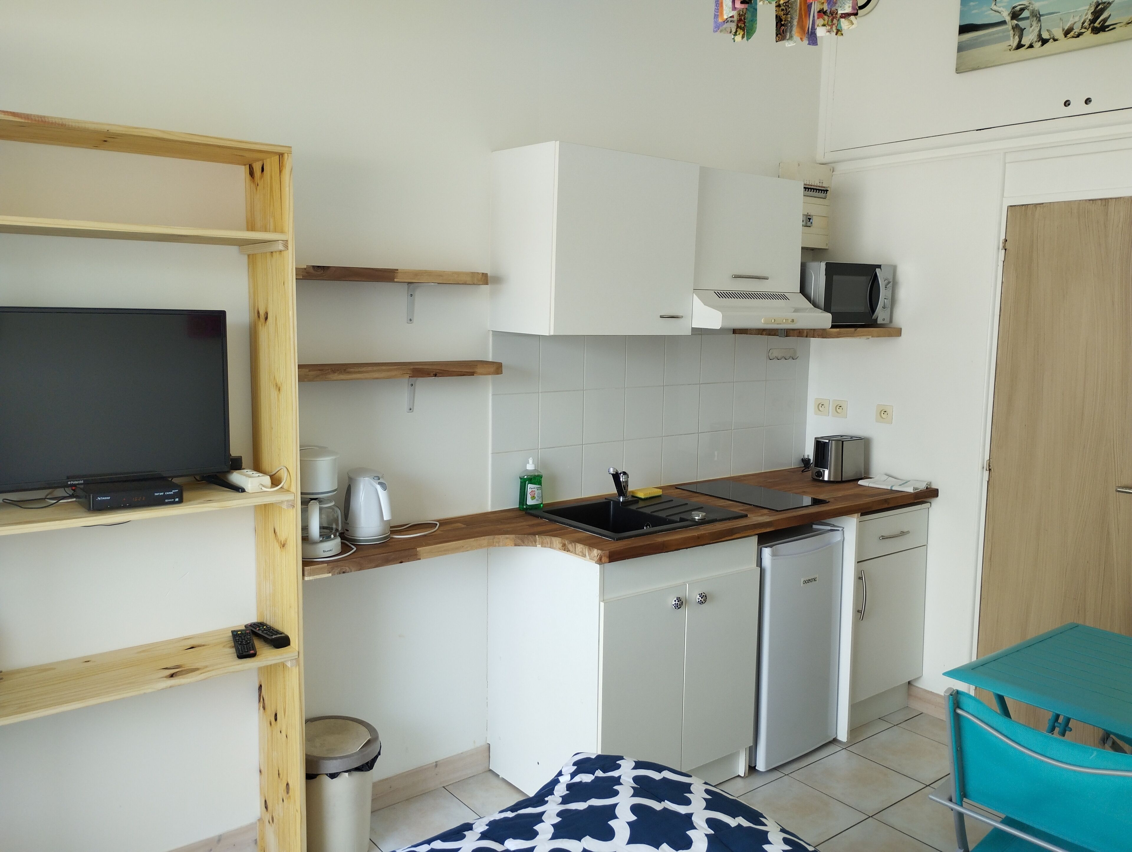 Una cucina compatta con TV, macchina del caffè e piccolo frigorifero.