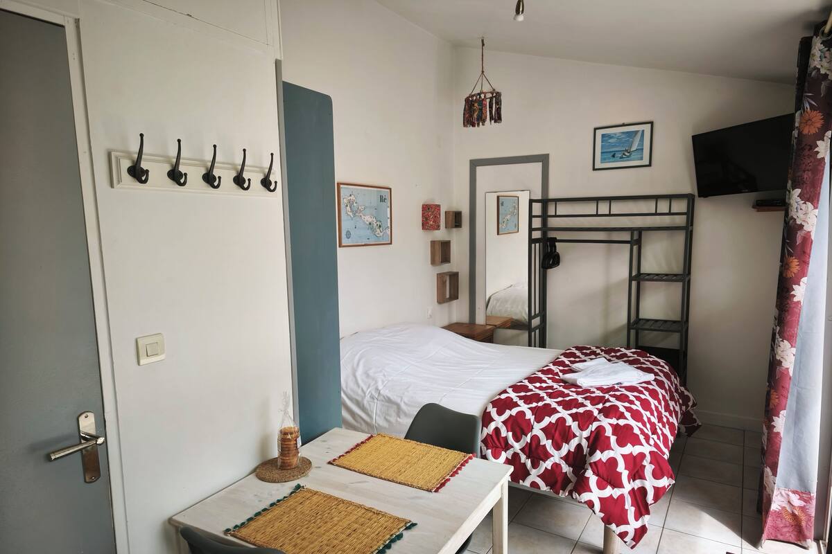 Une chambre de dortoir équipée d’un lit superposé, d’un bureau avec une chaise, d’une table avec un set de table et d’un luminaire suspendu.