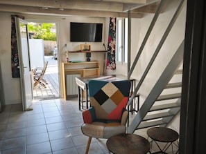 A room with a desk, chair, and a television mounted on the wall.