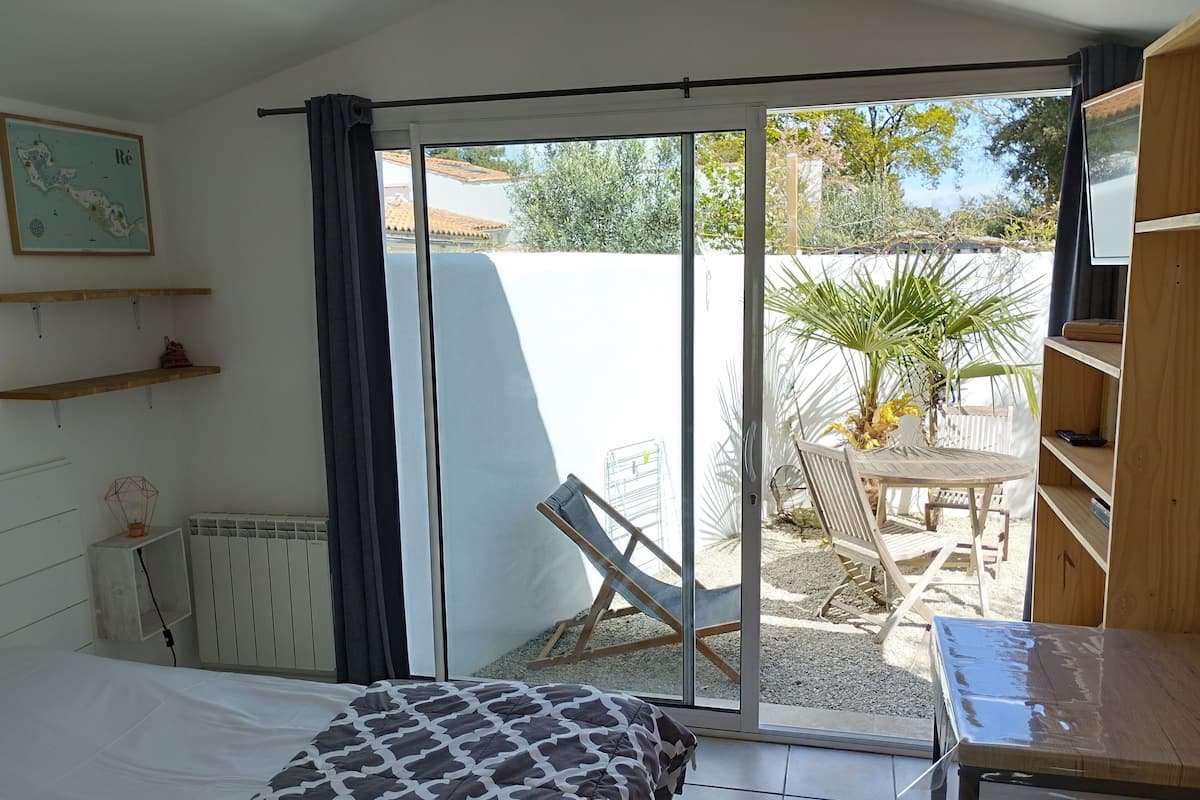 Une chambre à coucher avec un lit, un radiateur, une fenêtre avec des rideaux, une carte accrochée au mur et une vue sur l’extérieur.
