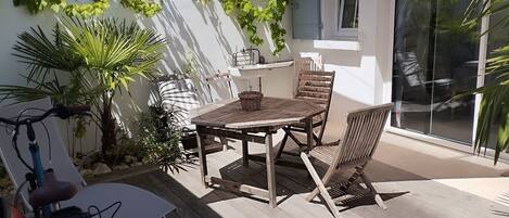 A patio with a wooden table and chairs, a bicycle, and a sunshade.