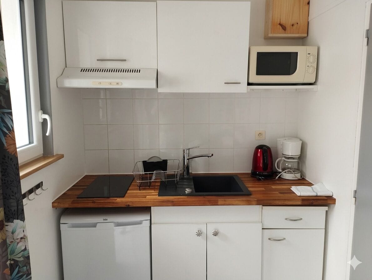 A compact kitchen with a built-in dishwasher, a microwave, a coffee maker, and a wooden countertop.