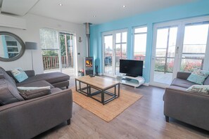 Una sala de estar moderna con sofá, mesa de centro, televisor y chimenea.