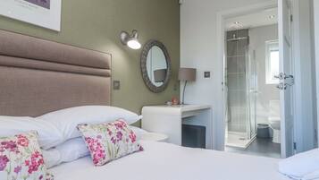 A hotel room with a bed, a bedside table, a mirror, a shower, and a toilet.