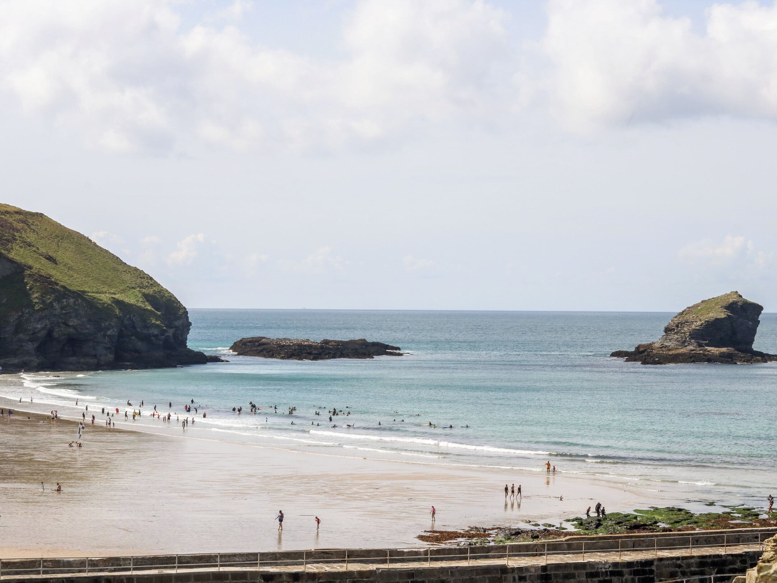 A beach with rocky outcrops, clear blue water, and a sandy shore.