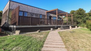 A modern building with a wooden facade, a covered outdoor area, and a stone pathway leading to the entrance. - Warleggan (Redruth)