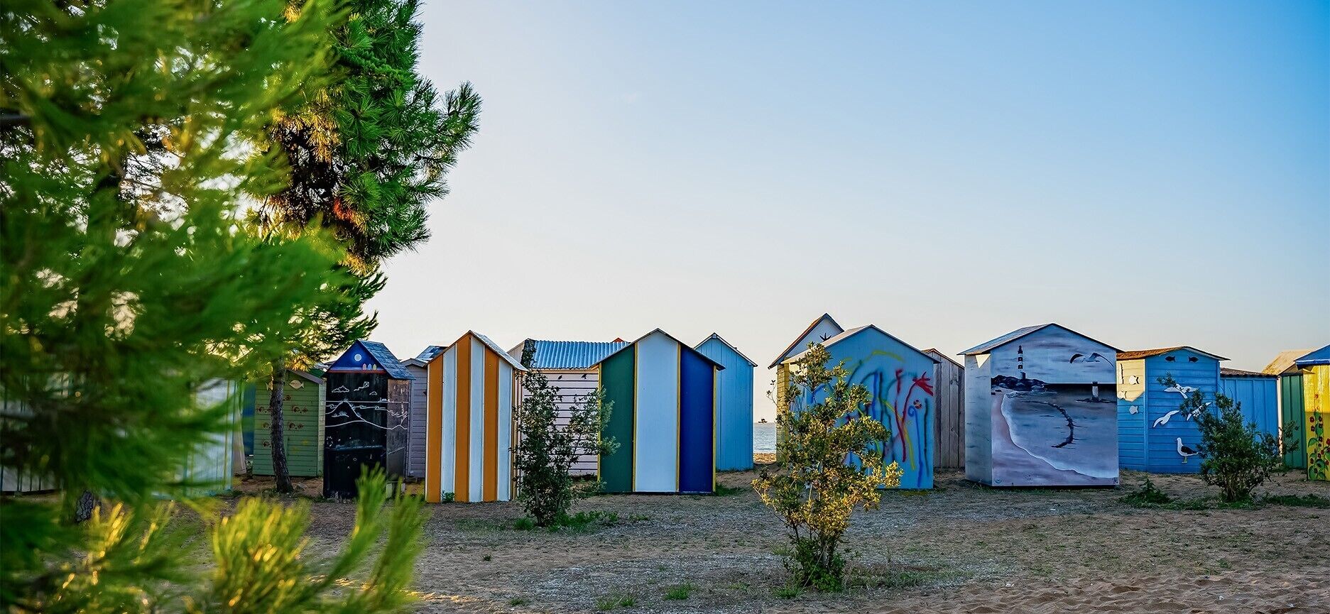 A row of beach huts with a clear view of the sea in the background.
