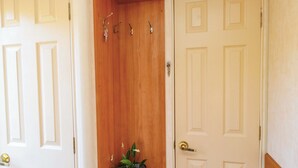 Un pasillo con un estante de madera, una planta en maceta y una puerta con picaporte de latón.