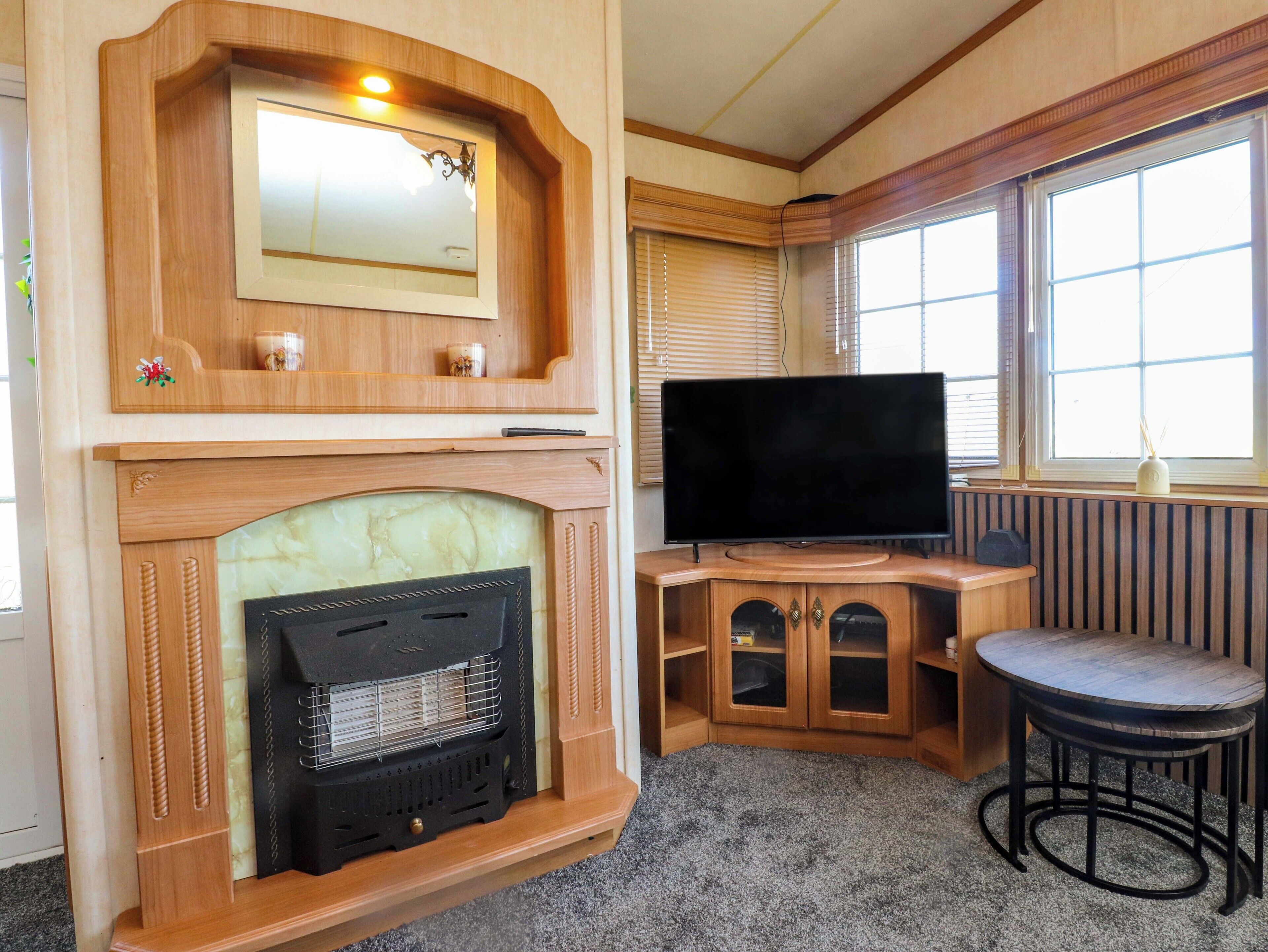 Una habitación acogedora con chimenea, televisión y ventana con persianas.