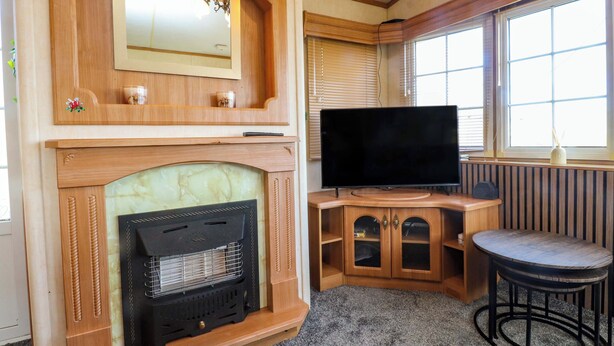 Una habitación acogedora con chimenea, televisión y ventana con persianas.
