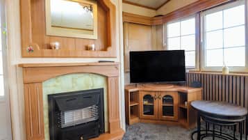 Una habitación acogedora con chimenea, televisión y ventana con persianas.