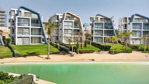 A modern hotel with multiple floors, a pool, and well-maintained gardens. - BirdNest At Fouka Bay (El Dabaa)