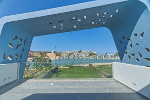 A modern architectural structure with geometric cutouts, overlooking a coastal area with buildings and a beach. - BirdNest At Fouka Bay (El Dabaa)
