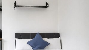 A neatly made bed with a striped blanket, a blue pillow, and rolled towels. - Hammersmith Stayz (London)