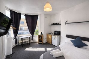 Une chambre d’hôtel avec un lit, un bureau, une télévision et une vue sur la ville.