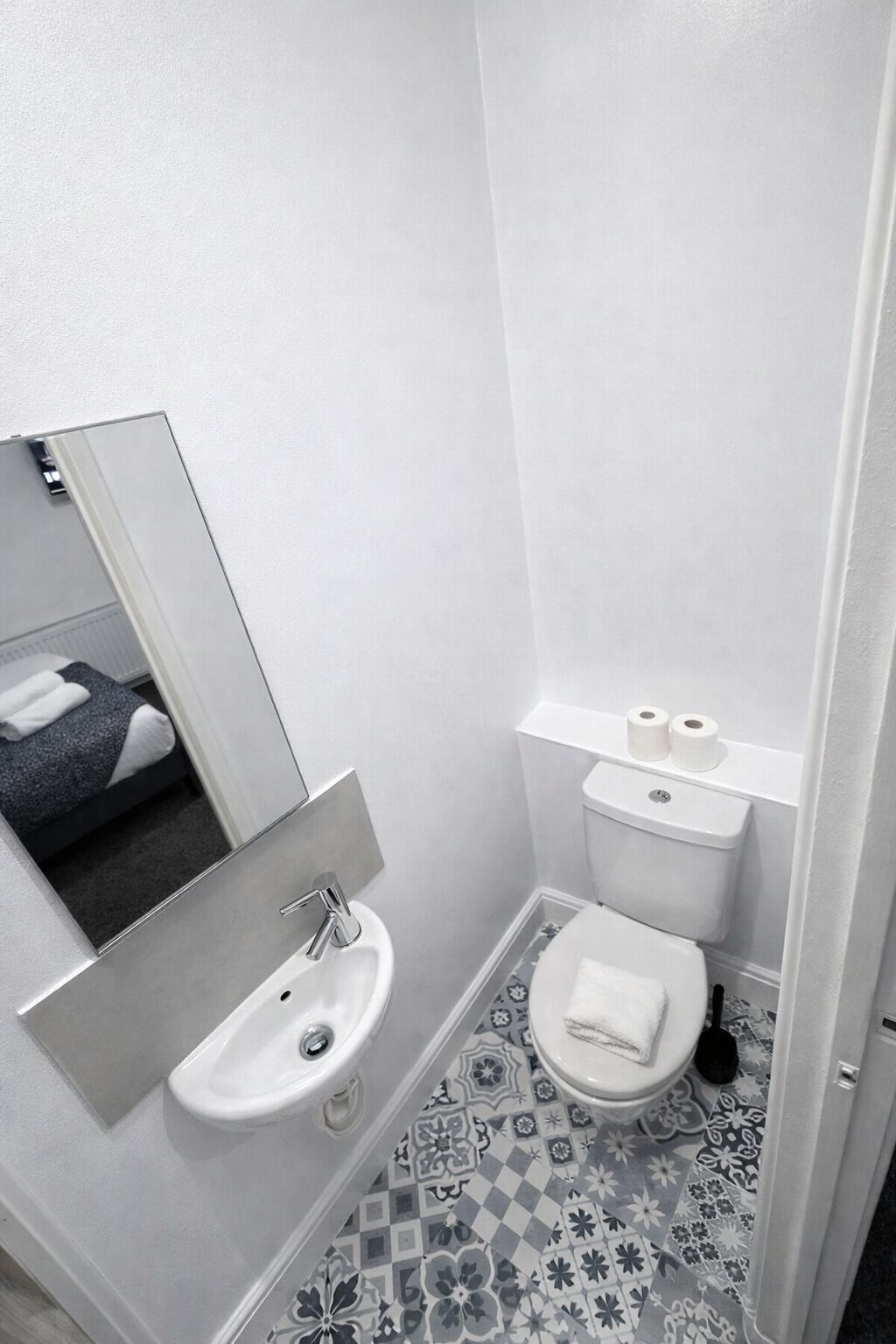 A bathroom with a sink, toilet, and mirror.