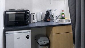 A compact kitchenette with a microwave, toaster, and small refrigerator. - Hammersmith Stayz (London)