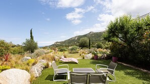 Un jardín con una mesa y sillas, rodeado de rocas y plantas.