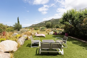 A garden with a table and chairs, surrounded by rocks and plants.