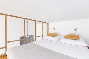 A bedroom with a bed, two pillows, a hanging light fixture, and a wall-mounted light. - Native Apartments Brzozowa 8 (Kraków)