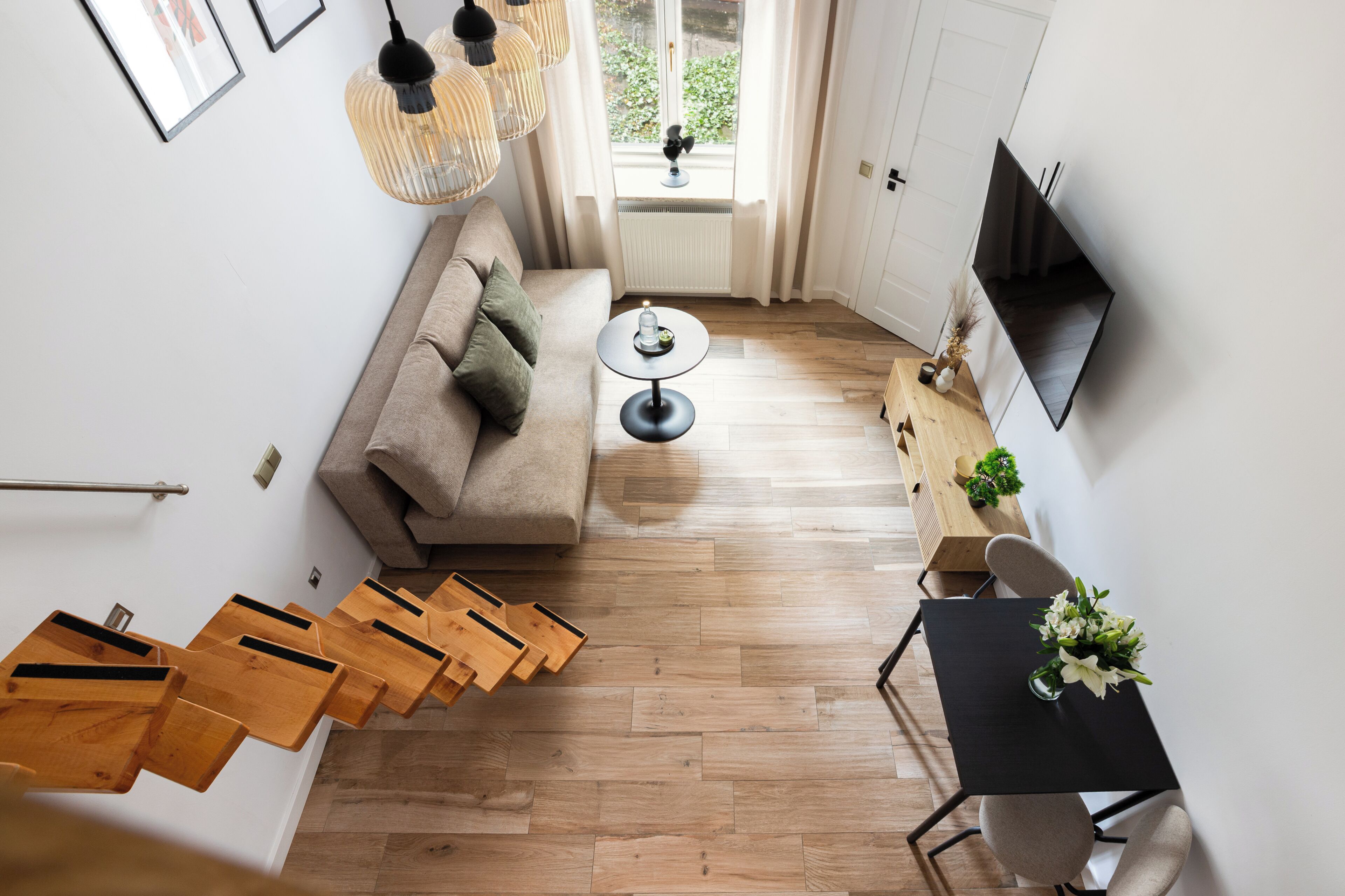 Una sala de estar moderna con un sofá, una mesa de centro, un televisor y una escalera de madera.