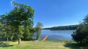 A grassy area with a dock extending into a lake, surrounded by trees.