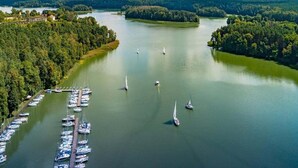 A marina with multiple boats docked and sailboats on the water. - Double room, sauna, Masuria (Ruciane Nida)