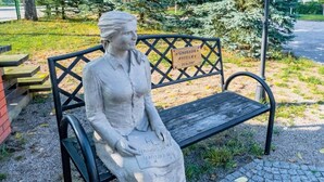 A statue of a seated woman on a bench with a plaque. - Double room, sauna, Masuria (Ruciane Nida)