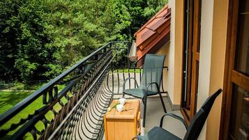 Un balcon avec une table, des chaises et une vue sur une zone boisée.