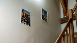A wooden staircase with a handrail, two framed pictures on the wall, and a plain wall. - Périgord. gite sleeps 8 or 12, 4*, private heated pool, large open spaces. (Lempzours)