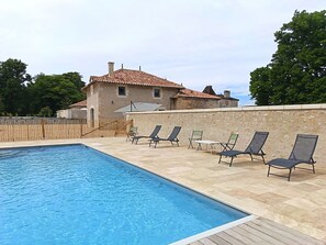 A swimming pool with lounge chairs and a stone wall. - Périgord. gite sleeps 8 or 12, 4*, private heated pool, large open spaces. (Lempzours)