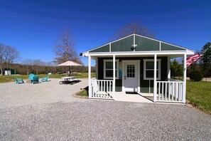 A small, single-story building with a porch, a welcome sign, and an American flag. - Tanya`s Lake Norfork Cabin (Calico Rock)