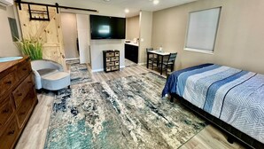 Une chambre à coucher comprenant un lit, un bureau, une chaise, une commode, un téléviseur et un ventilateur de plafond.