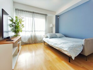 A bedroom with a bed, a desk with a computer, a lamp, and a window with sheer curtains. - Apartment 5 min. from the beach Palamós Costa Brava (Palamós)