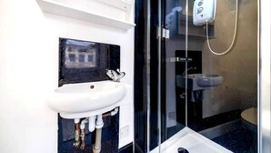 A bathroom with a white sink, a glass shower enclosure, and a visible toilet. - West Kensington Modern Couple Retreat (Greater London)