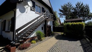 A house with a staircase leading to the entrance, a satellite dish, and a well-maintained garden. - Holiday apartment for 4 people, Rowy (Rowy)