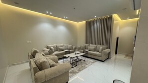 A modern living room with a sectional sofa, a coffee table, and a wall-mounted TV. - الشقق الفاخره luxury apartments (AL Madinah AL Munawwarah)