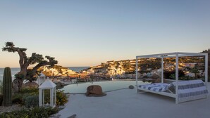 A rooftop pool with a bed and a view of a coastal town.