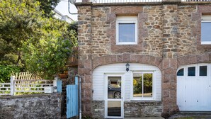 Ein Steinhaus mit Garage, einer weißen Tür und einer Satellitenschüssel.