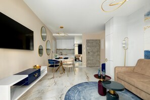 Una sala de estar moderna con un televisor de pantalla plana, un comedor con una mesa de mármol y una cocina al fondo.