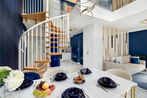 Ein modernes Interieur mit einer Wendeltreppe, einem Essbereich mit weißem Tisch und einer Wohnbereich mit einer Couch.