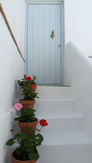 Una escalera blanca con una puerta azul claro al final.