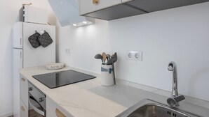Una cocina moderna con horno empotrado, estufa, pileta y encimera con hervidor y especias.