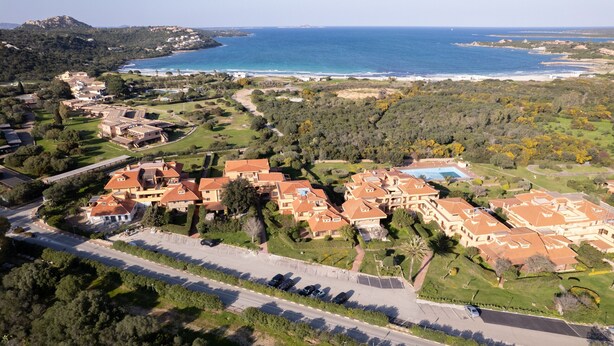 An aerial view of a coastal residential area with houses, a swimming pool, and a road. - Alba Marina by Wonderful Italy (Olbia)