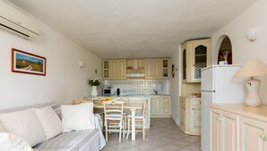 A compact living space with a kitchenette, a dining area, and a sofa. - Alba Marina by Wonderful Italy (Olbia)