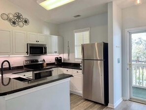 A modern kitchen with white cabinets, stainless steel appliances, and a large island. - Peaceful 2Bed/2Bath Condo | King Bed | Pool View (North Myrtle Beach)