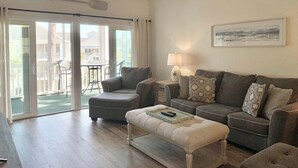 Ein Wohnzimmer mit einer Couch, einem Hocker und einem Deckenventilator.