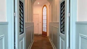 A hallway with arched ceilings, a central door, and a view into a room with a window.